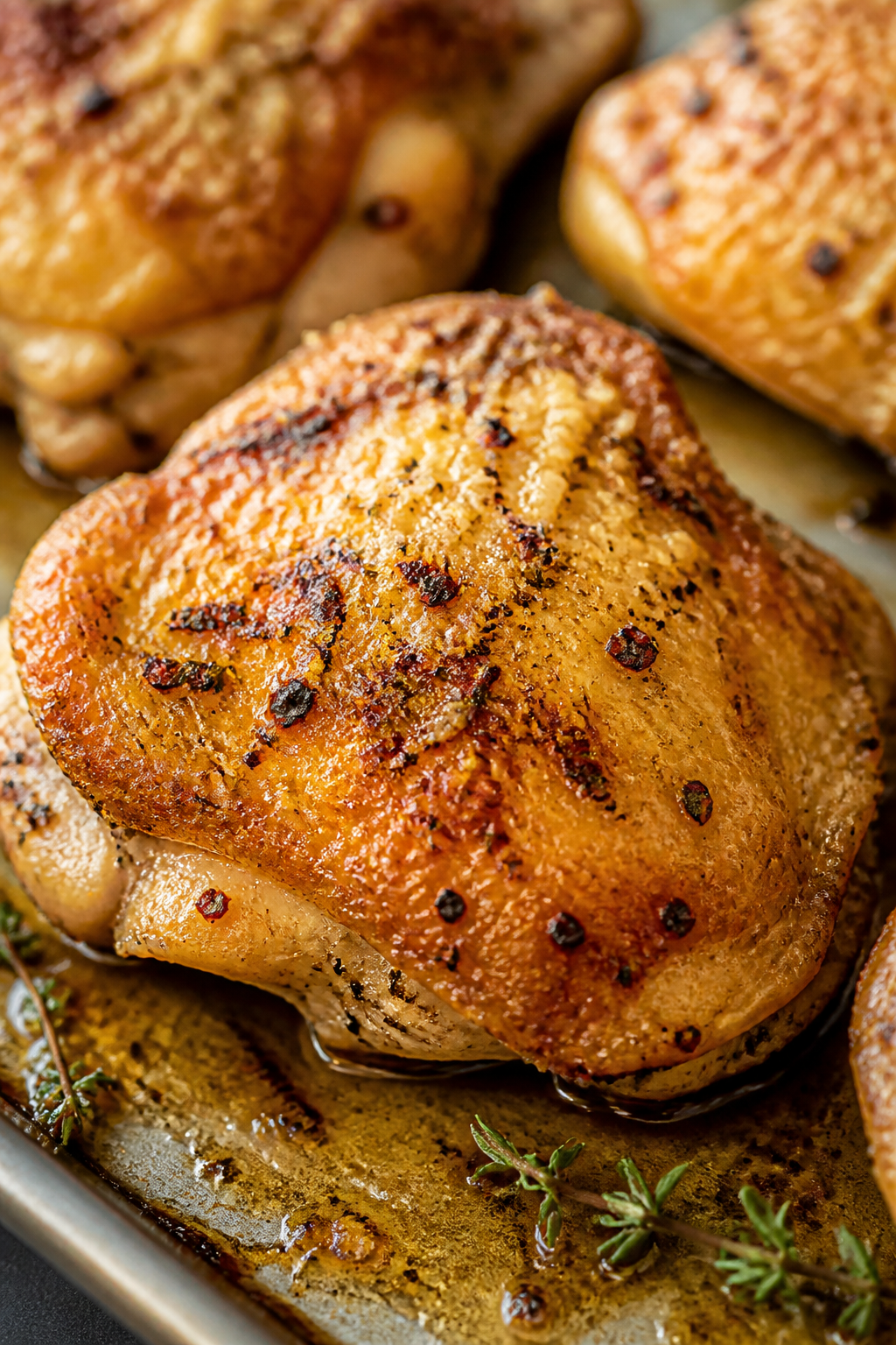 Close-up detail: Crispy garlic-Parmesan chicken thigh fresh from the oven, skin blistered and deep g