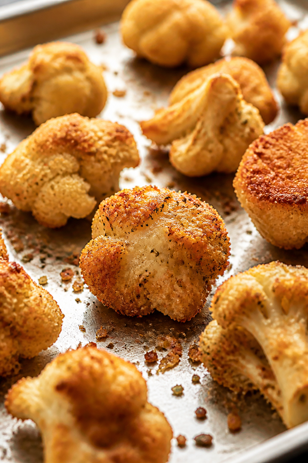 Close-up detail: Golden-brown Parmesan-crusted cauliflower nuggets just out of the oven on a preheat