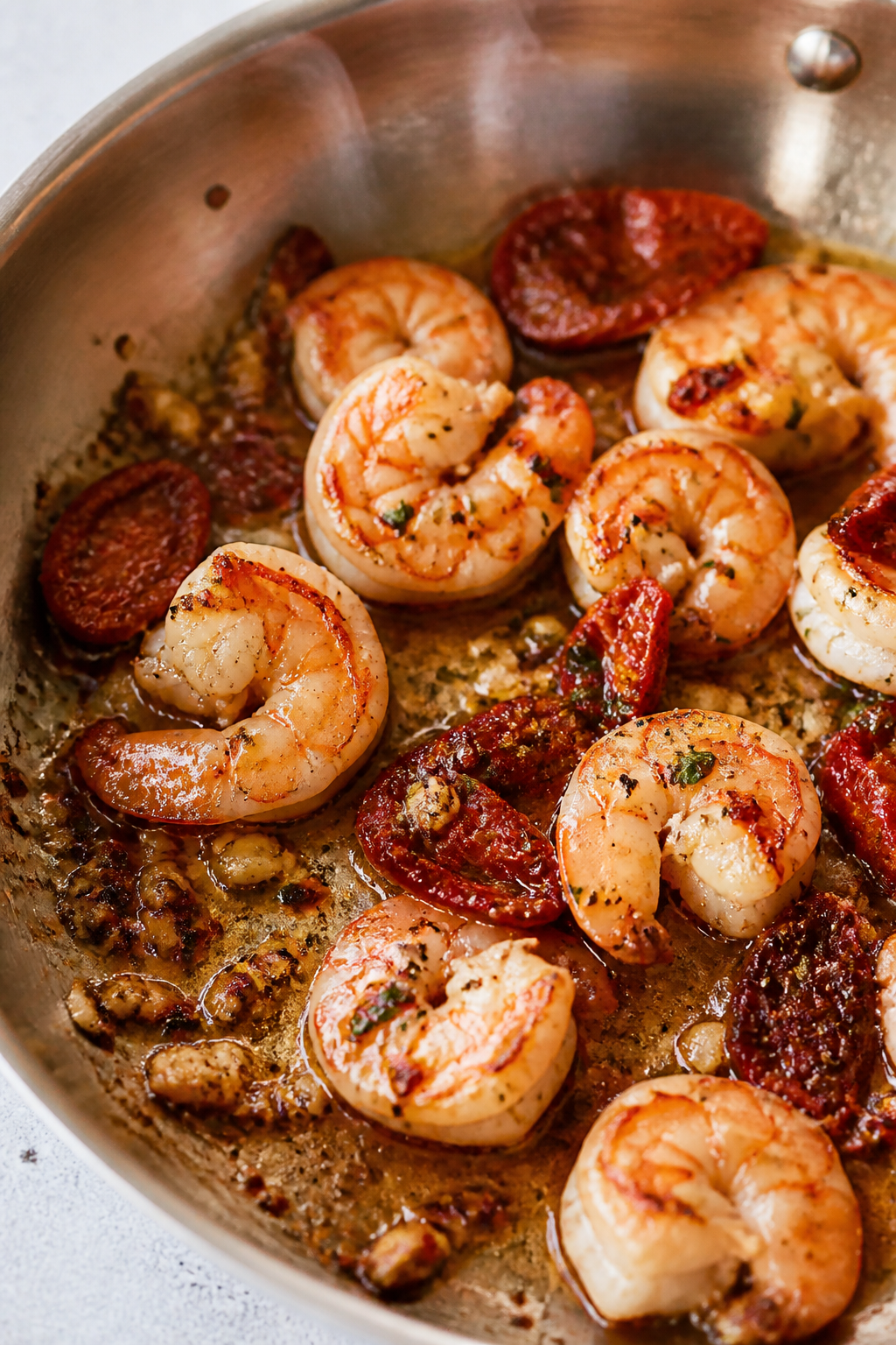 Cooking process, close-up detail: Searing large shrimp in a stainless skillet, just-opaque with ligh