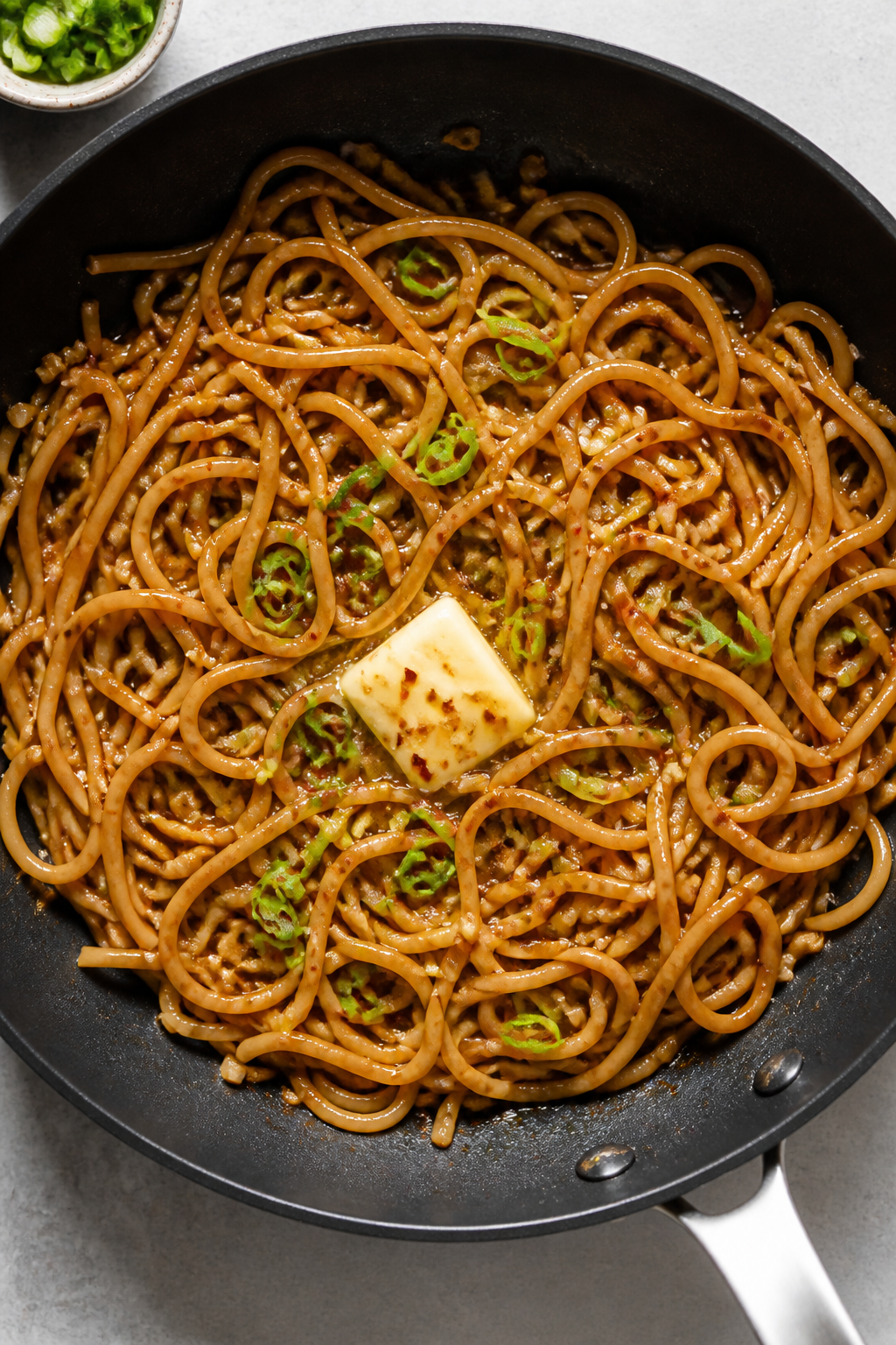 Cooking process: Garlic-butter noodles being tossed in the same pan—yakisoba/lo mein strands coate