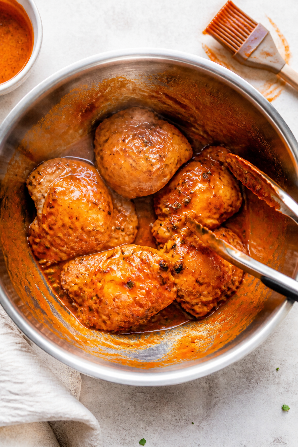 Cooking process: Overhead shot of sauced Buffalo Ranch chicken thighs being tossed in a large stainl