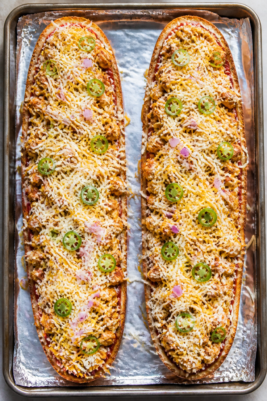 Cooking process: Overhead shot of the assembled French bread halves on a foil-lined sheet pan right 