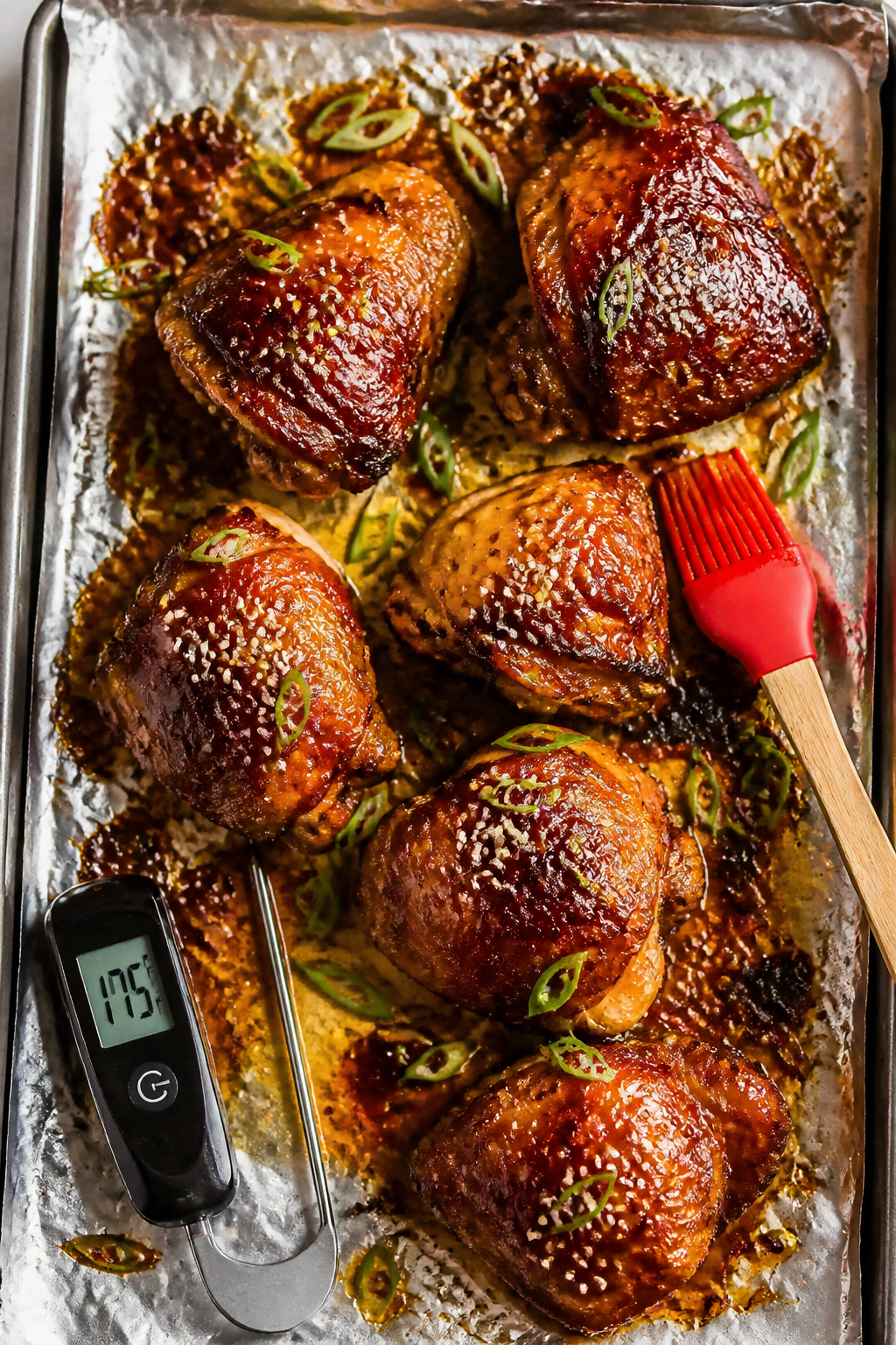 Overhead “tasty top view” of oven-roasted sweet chili chicken thighs resting on a foil-lined she