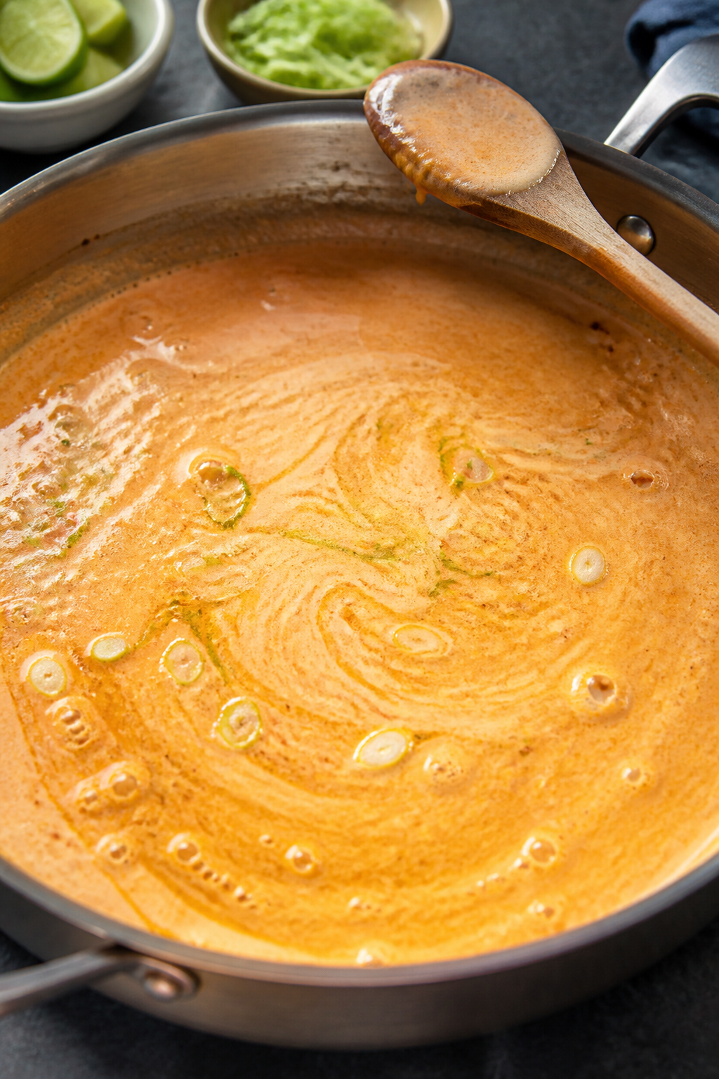 Sauce-building beauty shot: Silky creamy sriracha sauce gently bubbling in a skillet, ribbons of ora