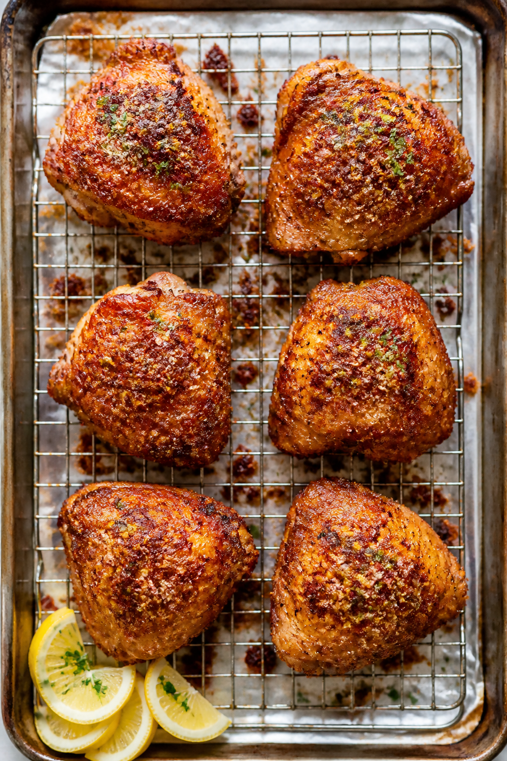 Tasty top view: Overhead shot of a rimmed baking sheet with six finished chicken thighs on a wire ra