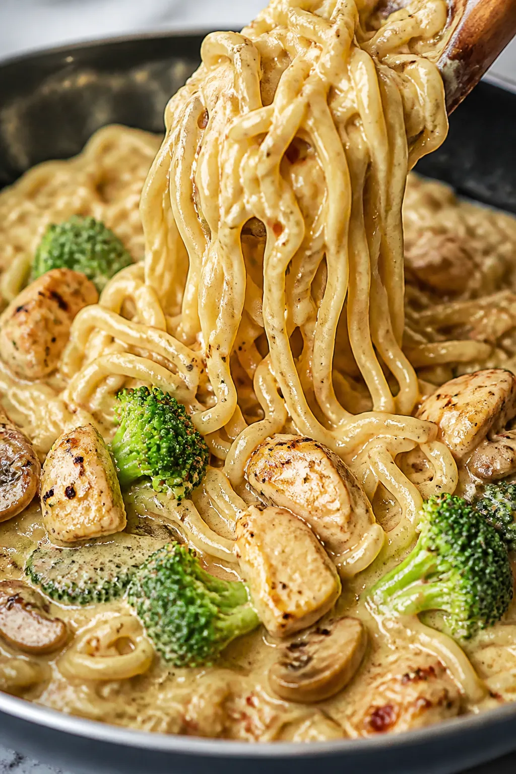 Close-up creamy noodle detail: Ultra close-up of creamy chicken ramen mid-toss in the skillet, silky