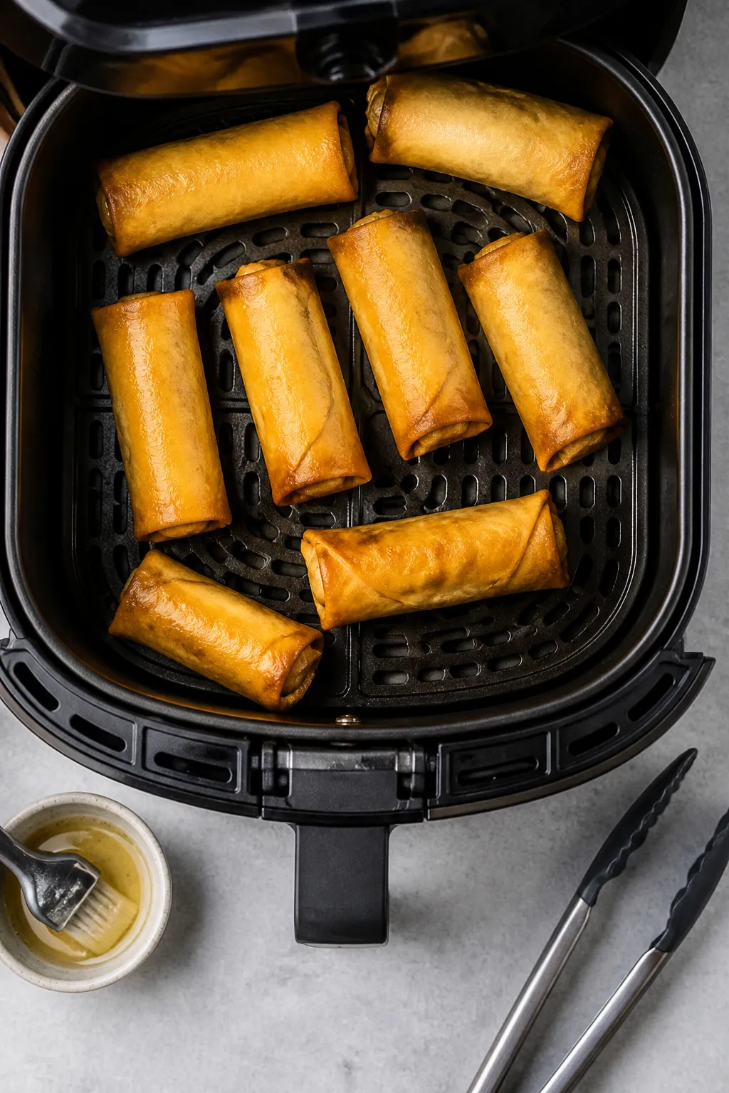 Cooking process: Air fryer basket at 375°F filled with neatly spaced, lightly oiled egg rolls mid-c