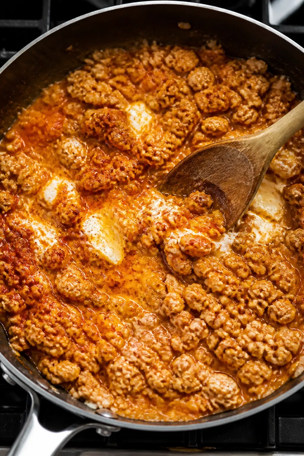 Cooking process: Buffalo chicken filling being folded together in a skillet—ground chicken browned