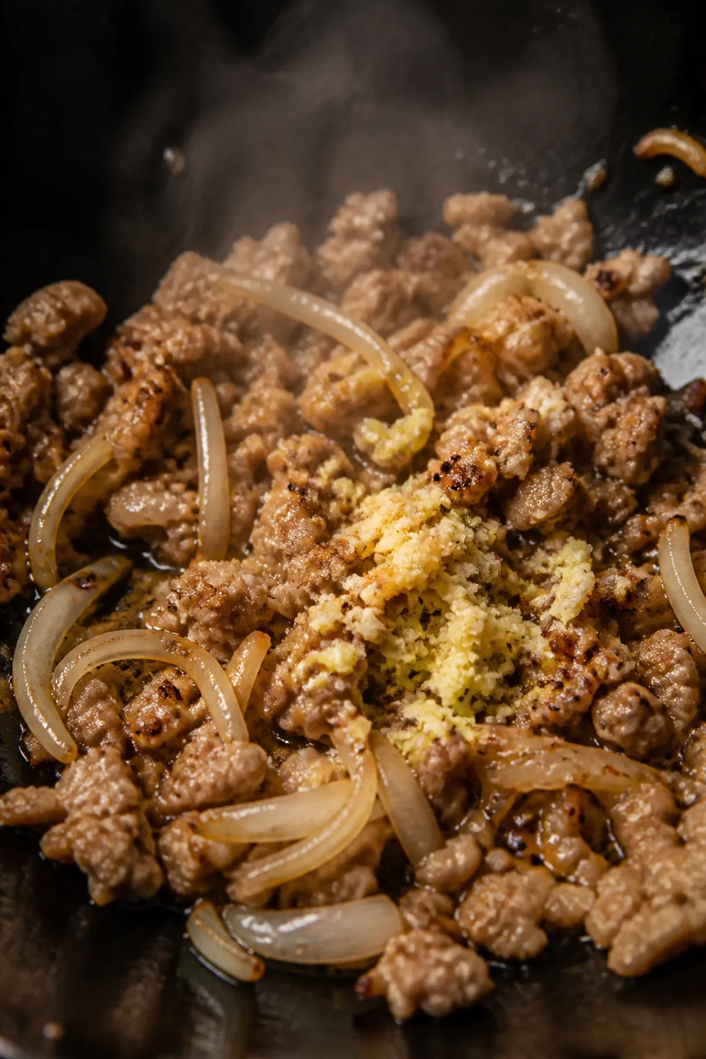 Cooking process, close-up: Ground chicken browning in a sizzling wok with lightly caramelized edges,