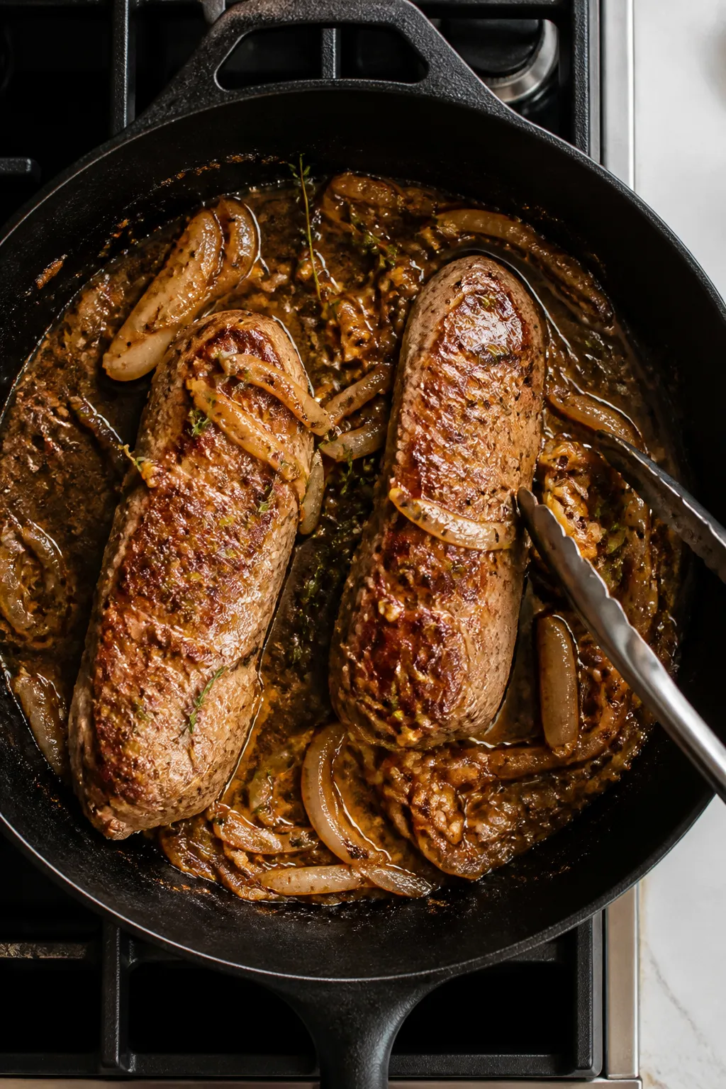 Cooking process: Overhead shot of a hot oven-safe skillet on the stovetop with the pork tenderloin m
