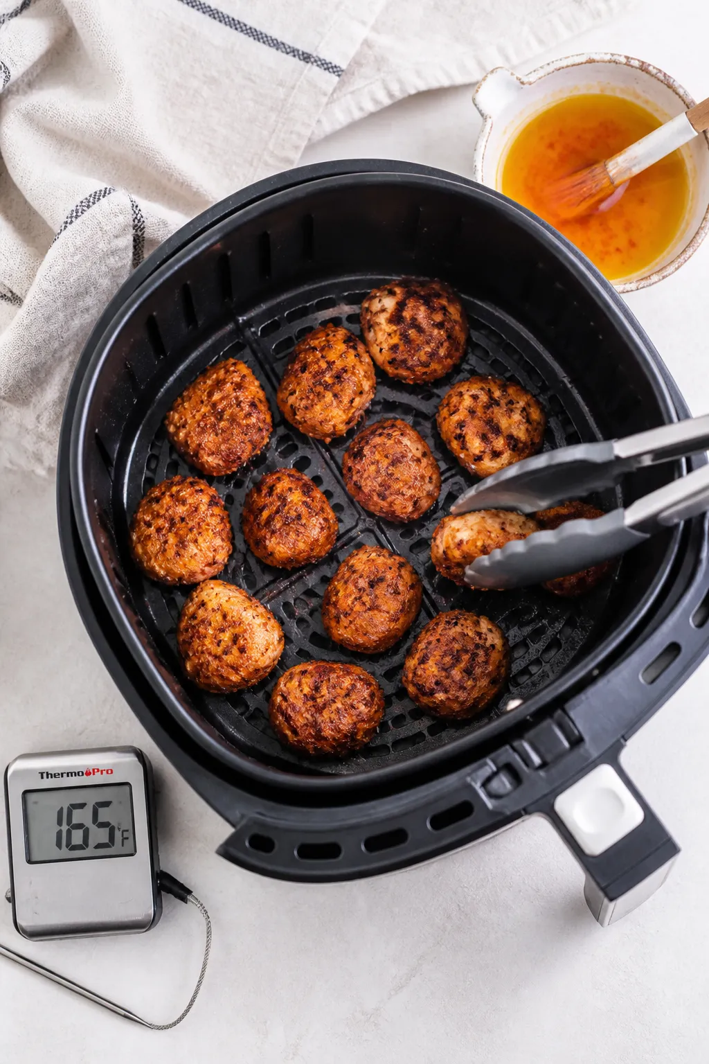 Cooking process: Overhead shot of cooked bites in an air fryer basket mid-batch, evenly spaced with 
