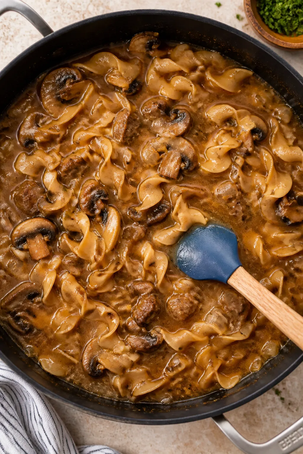 Cooking process: Overhead shot of the one-skillet stroganoff simmering after broth and uncooked whol