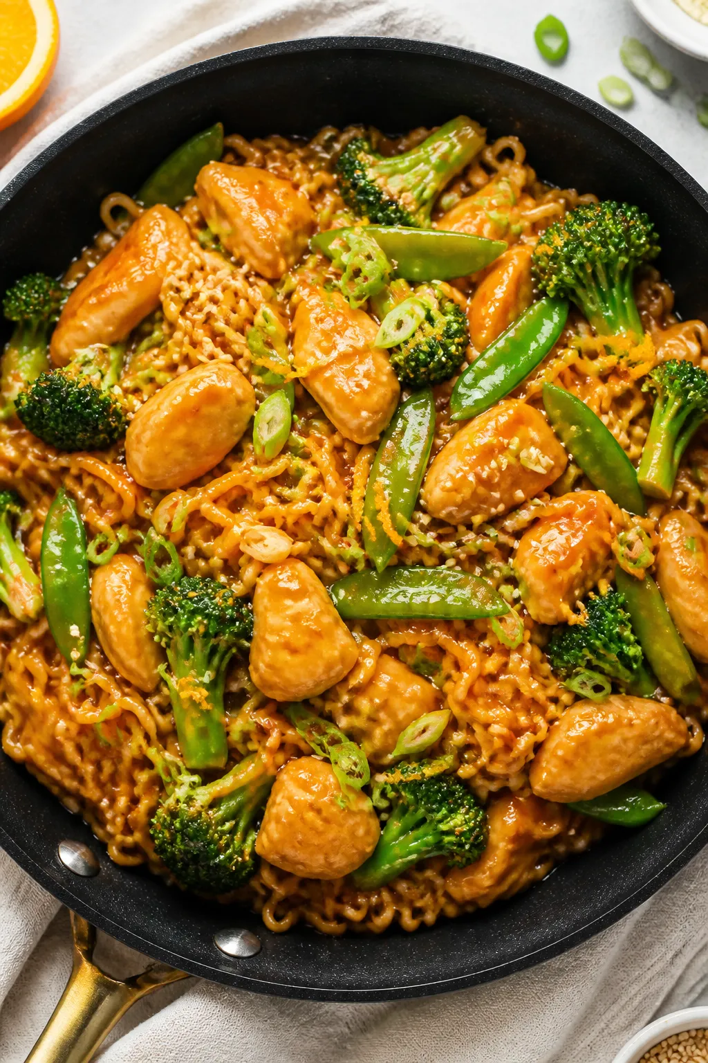 Tasty top view: Overhead shot of Easy Orange Chicken Ramen tossed in the skillet—bouncy ramen nood