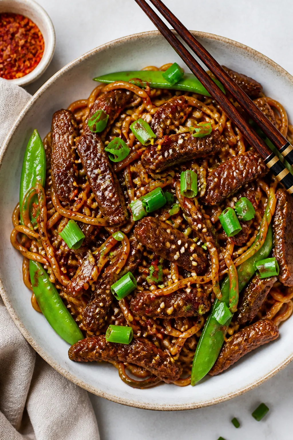 Tasty top view — Overhead shot of Mongolian Beef Ramen in a wide, shallow ceramic bowl: springy ra